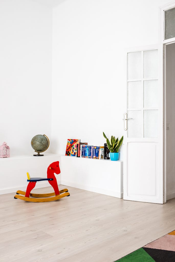 Bright minimalist kids room featuring a red wooden rocking horse, plants, and globe.