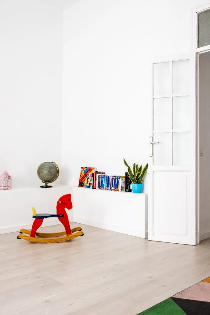 Bright minimalist kids room featuring a red wooden rocking horse, plants, and globe.