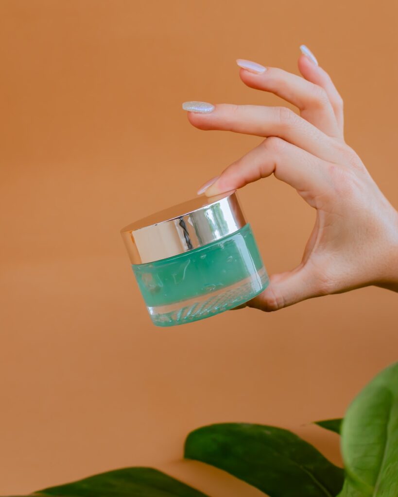 person holding clear glass bottle with green liquid